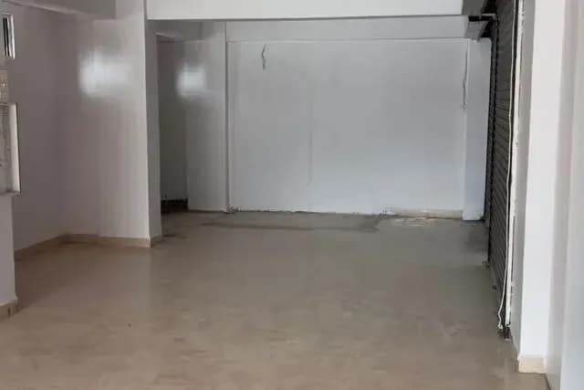 Empty interior of the commercial shop with tiled floor and shutter
